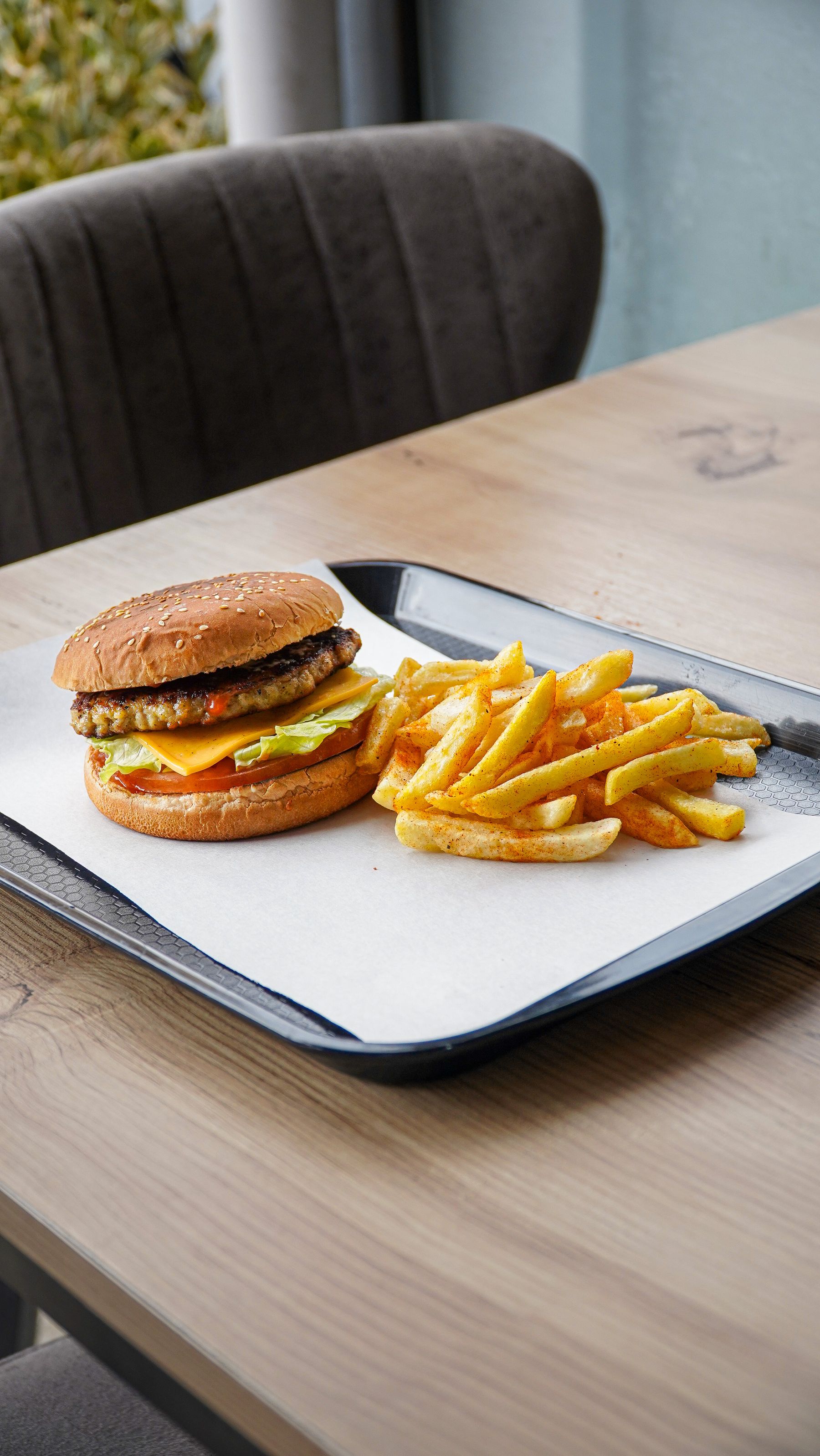 Freshly prepared crispy chicken burger and seasoned fries on a tray
